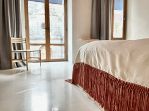 Cotton blanket with rust fringe in architectural space.