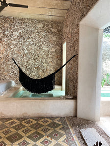 Black woven hammock in architectural space with fringe.