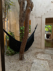 Black woven hammock in architectural space with fringe.