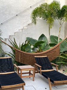 Poolside scene with gold hammock at luxury villa. Tulum style home decor.