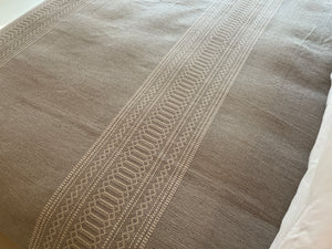 Woven artisan detail on gray and white bedcover.