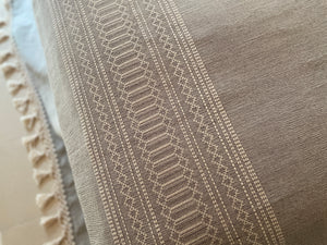 Woven artisan detail on gray and white bedcover.