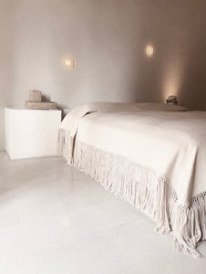 Textured white blanket in architectual space. Bedcover has fringe. Made in Oaxaca Mexico.