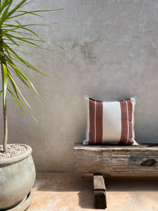 Natural fabric pillow handwoven with terracotta stripe.