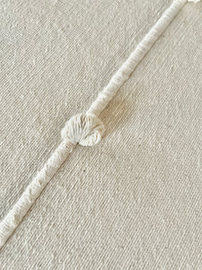 Woven artisan detail on white bedcover.