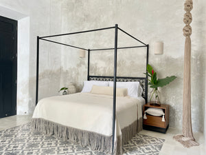 Architectural bedroom with giant tassel, handwoven gray and white bedcover with fringe. Collection of fringe pillows.
