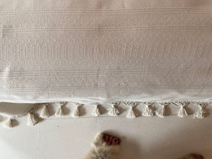 Fringe detail on handwoven blanket. Natural white bedcover.