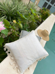 Collection of floor pillows in gray and natural white displayed poolside.