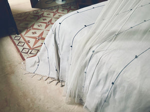 Black and white think striped bedcover in elegant room. Handwoven blanket with fringe on tile interior design floor.