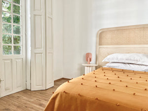 Golden blanket with bobble detail in elegant room. Parisian look with handmade bedcover .